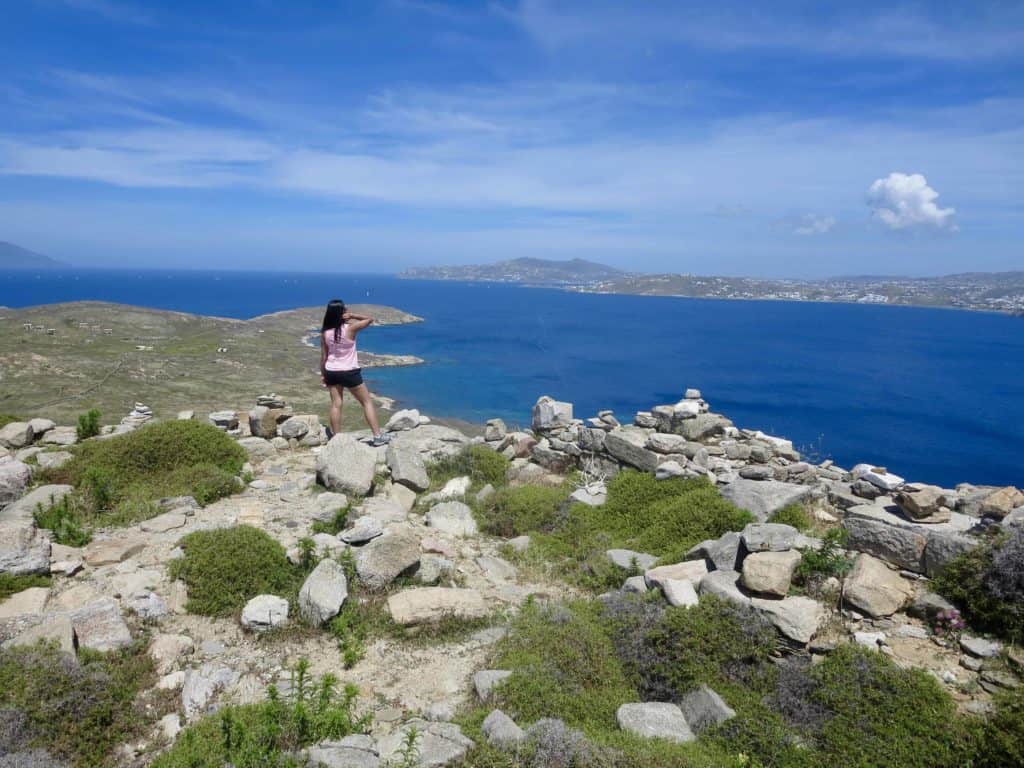 girl with pink top and shorts looking at the sea in Greece