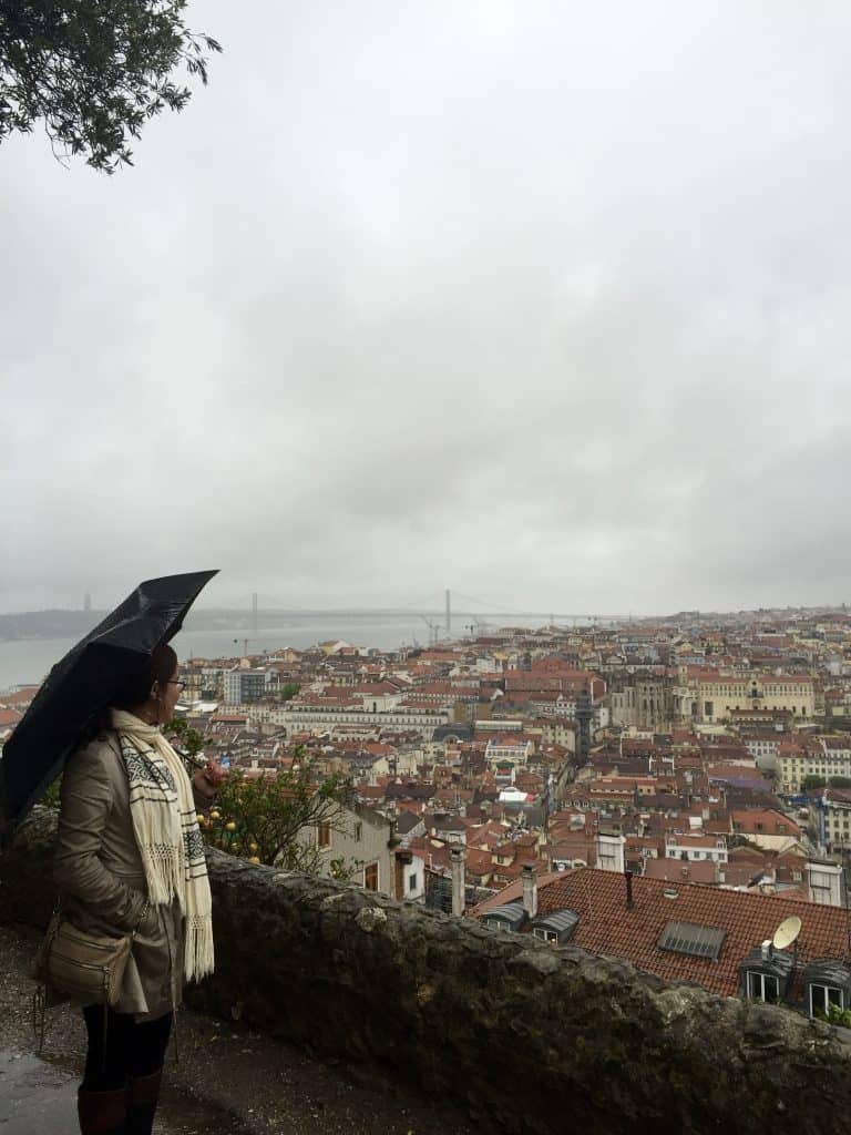 girl staring off into European city on a rainy day with a black umbrella