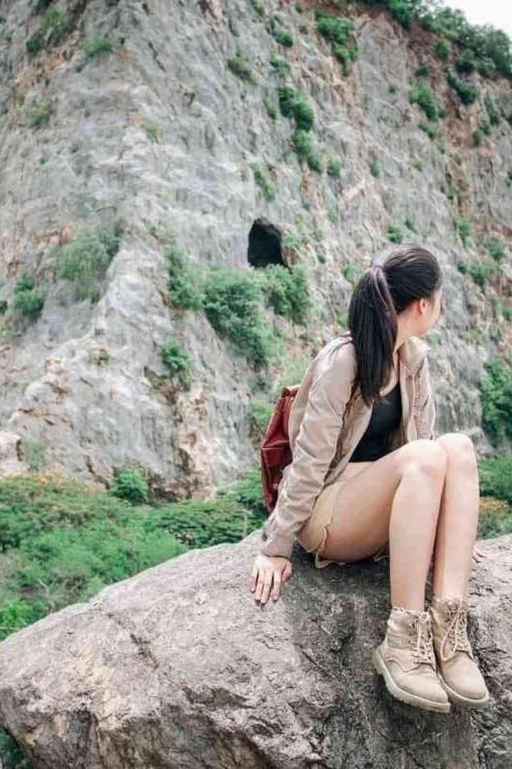 girl sitting on a mountain looking behind her at the nature