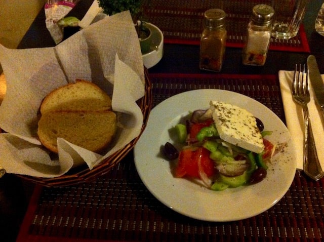 greek salad and a basket of bread 