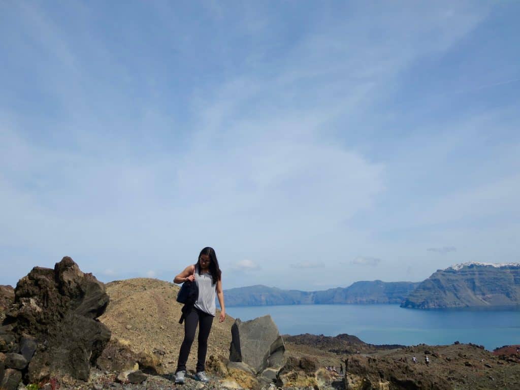 girl with grey shirt and black pants on an island in Greece, with blue skies and blue waters