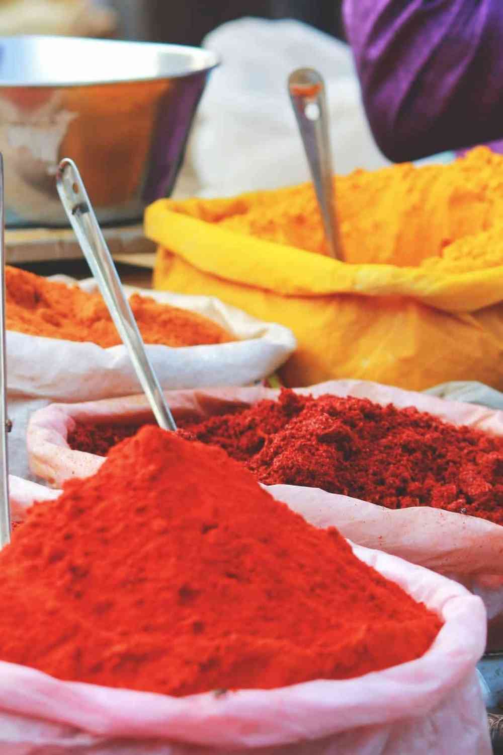bags of colorful spices inside an Indian market with a spoon