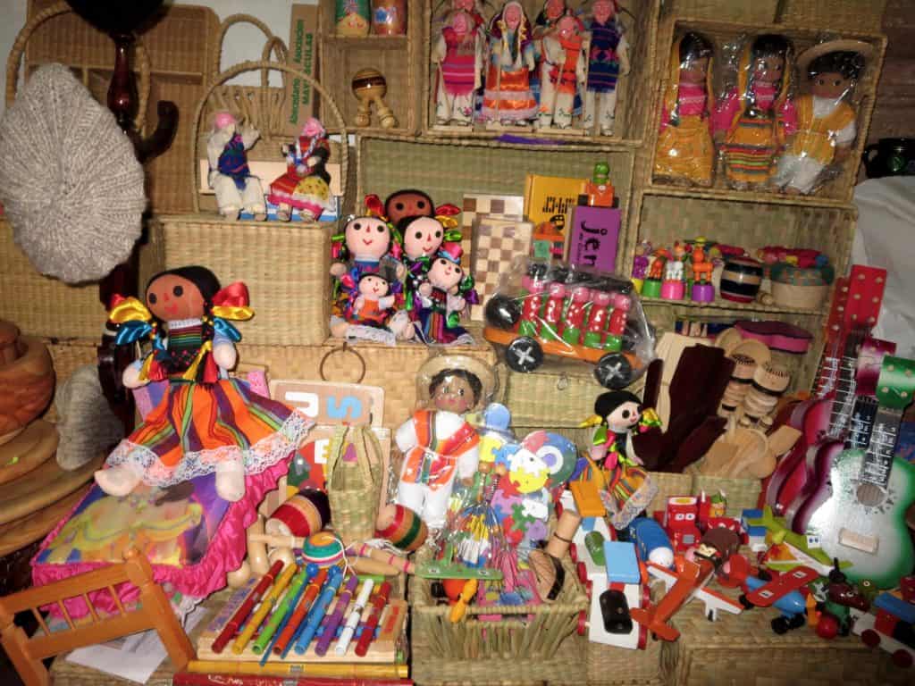 A picture of Mexican souvenirs, hand-made dolls, guitars, and colorful Mexican toys. 