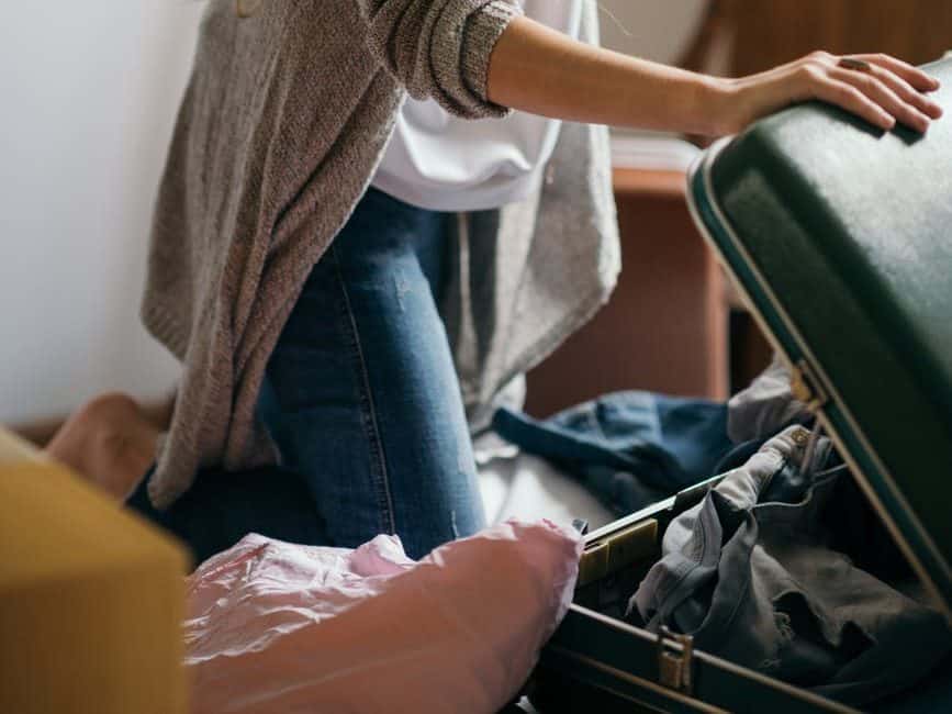 focused woman packing suitcase in bedroom