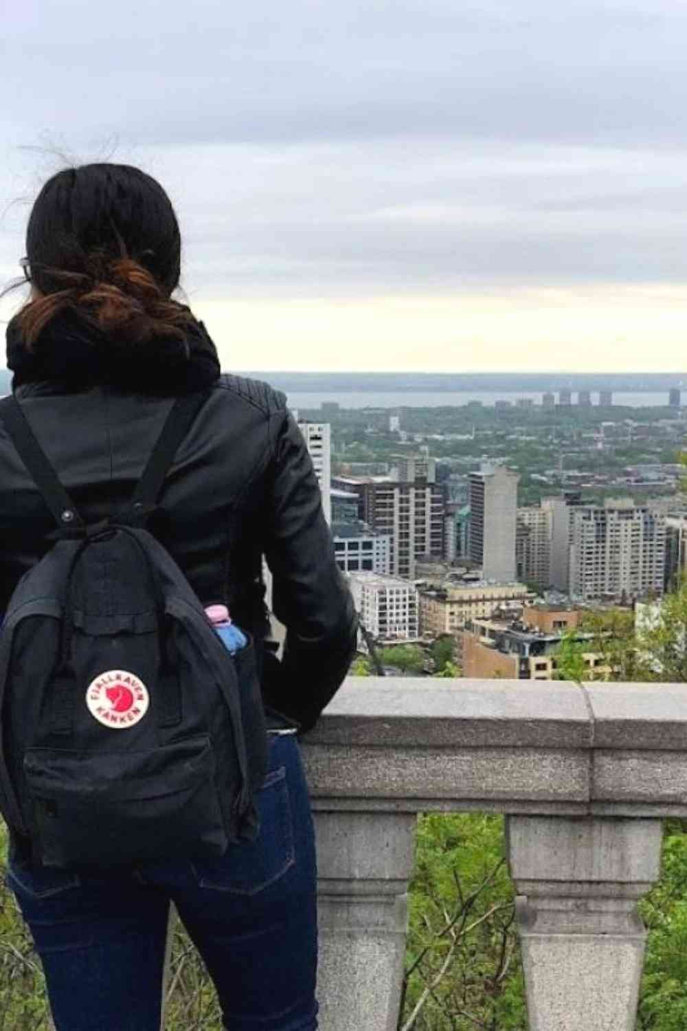 girl looking onto the city of Montreal with her backpack and a leather jacket on