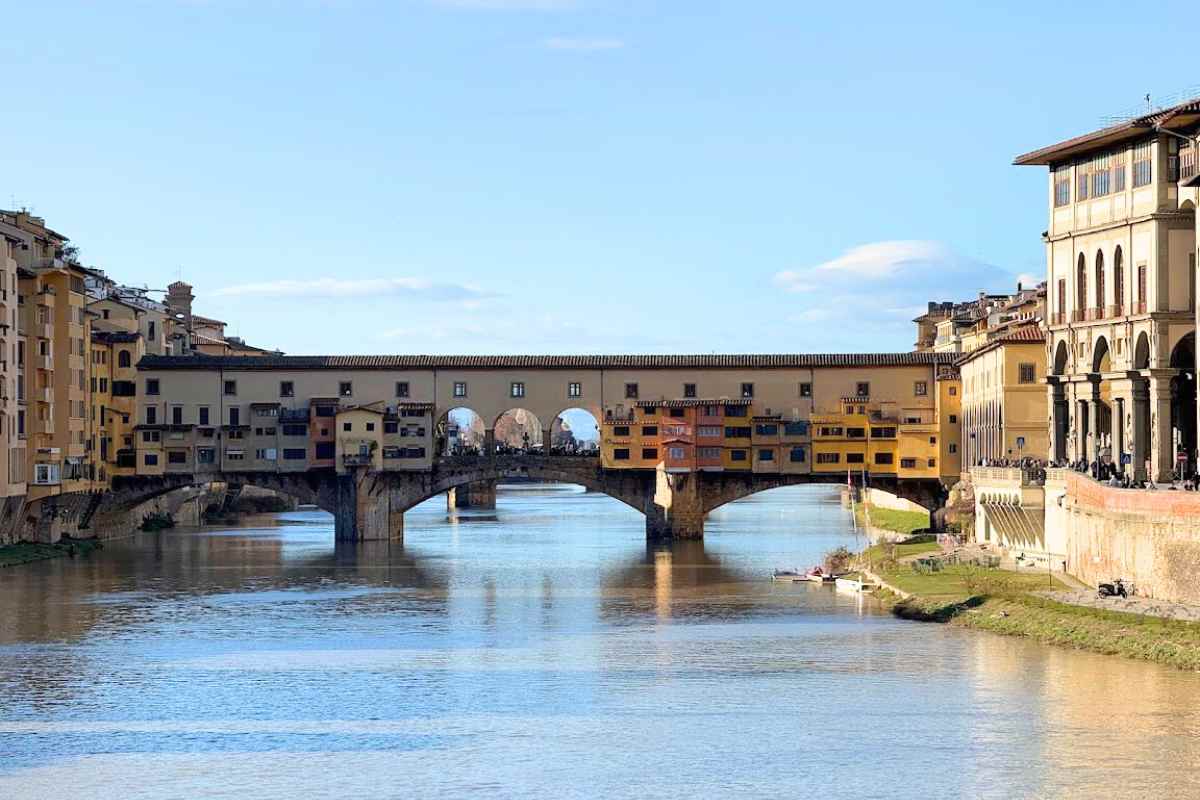 A scenic view of Ponte Vecchio in Florence, Italy, a famous historic bridge lined with shops, capturing the beauty of travel memories before you return home from traveling.
