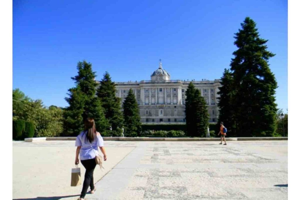 girl with blue shirt walking towards Royal Palace of Madrid