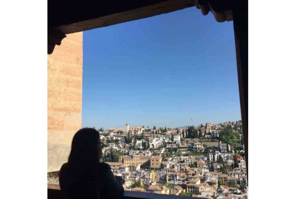 Girl standing inside Alhambra in Granada looking out the window 