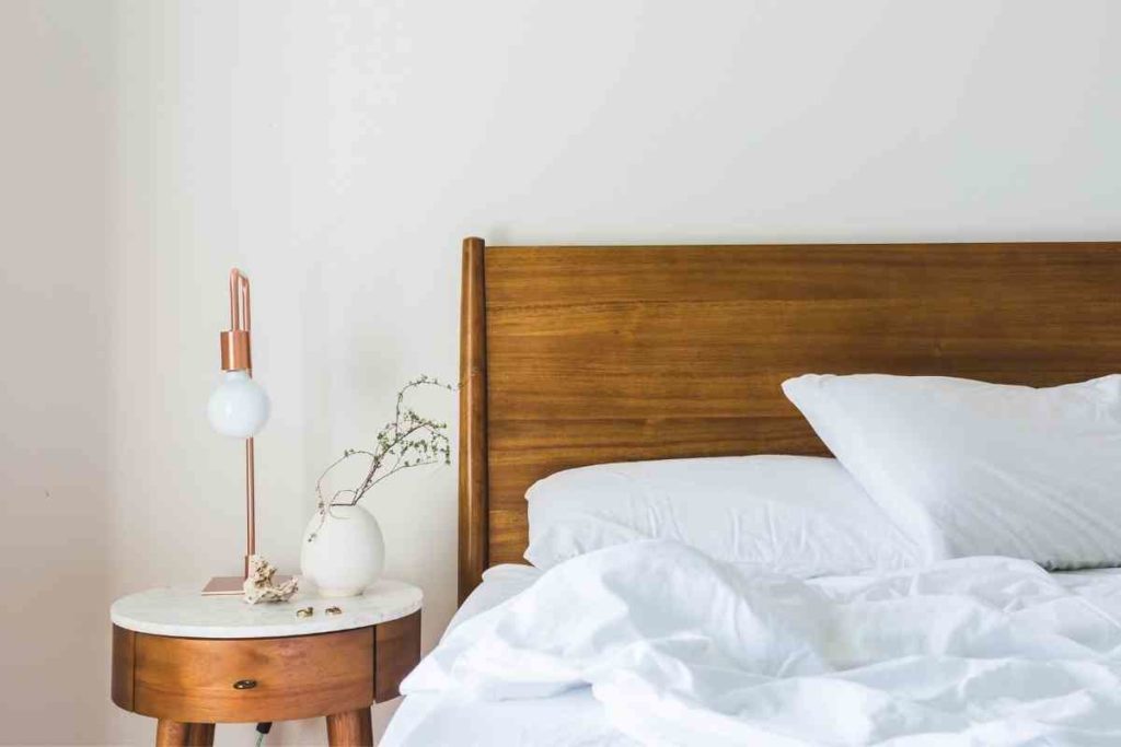 comfortable bed with white sheets and bedside table with lamp