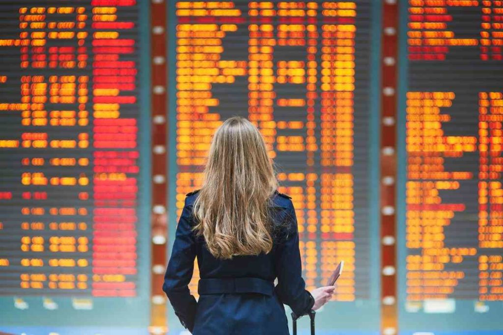 girl standing in front flights and departures screen