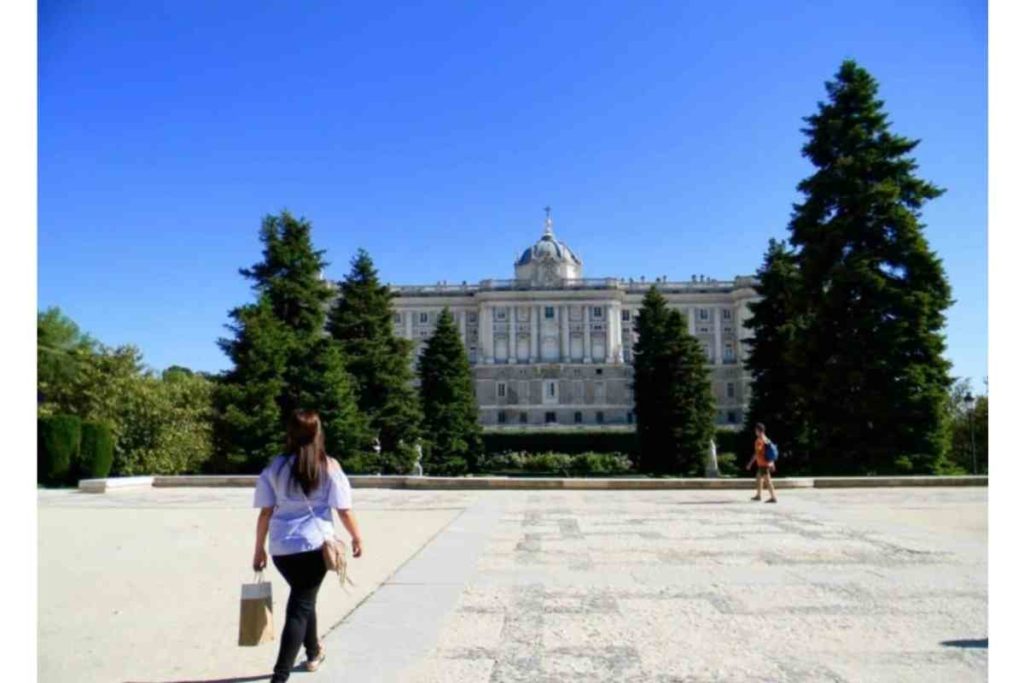 ni de aqui ni de alla girl in blue shirt walking towards Royal Palace of Madrid