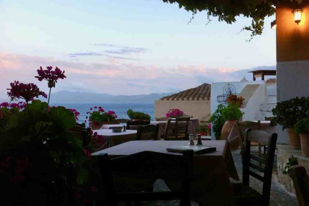 Restaurant tables and chairs with pink flowers in Monemvasia, Greece