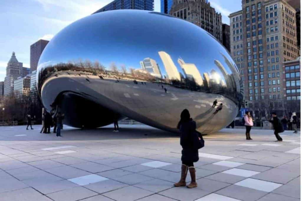 girl with winter coat standing next to Chicago cloudgate