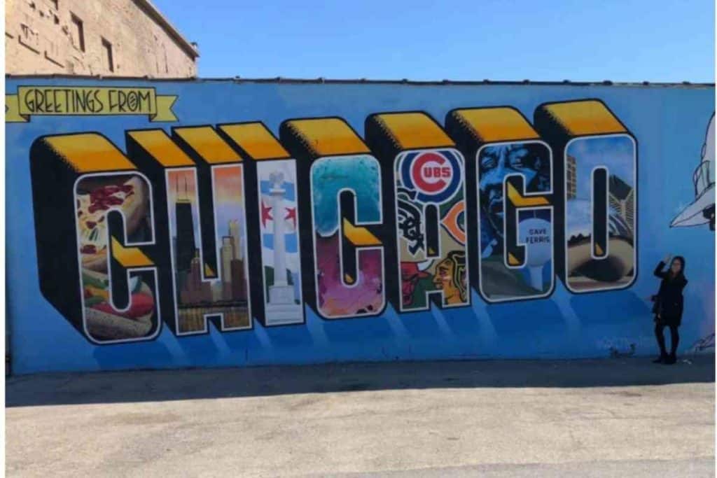 girl standing next to "Greetings from Chicago" mural in Chicago, IL.