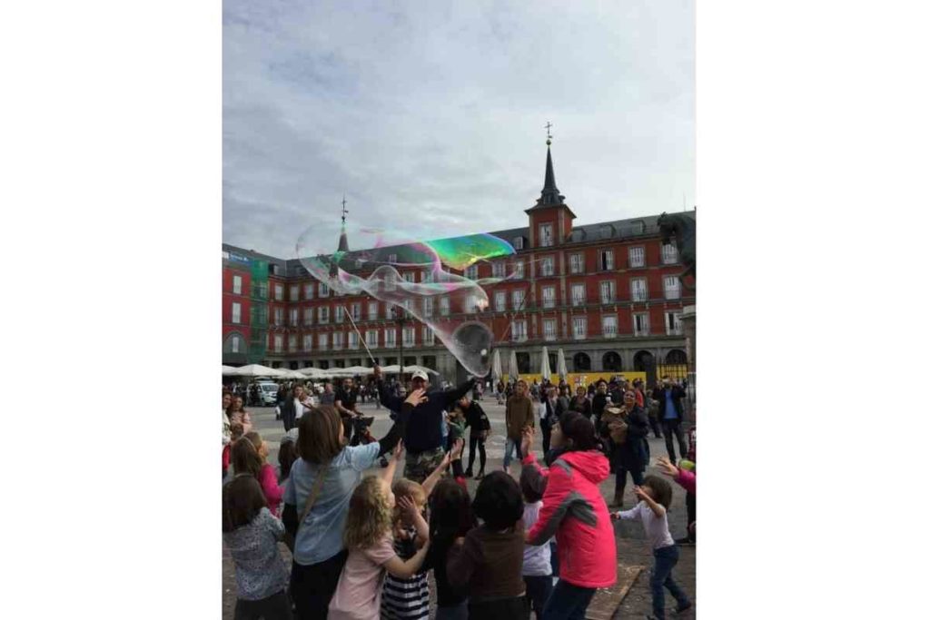 children playing with soap baloons in plaza mayor, madrid spain