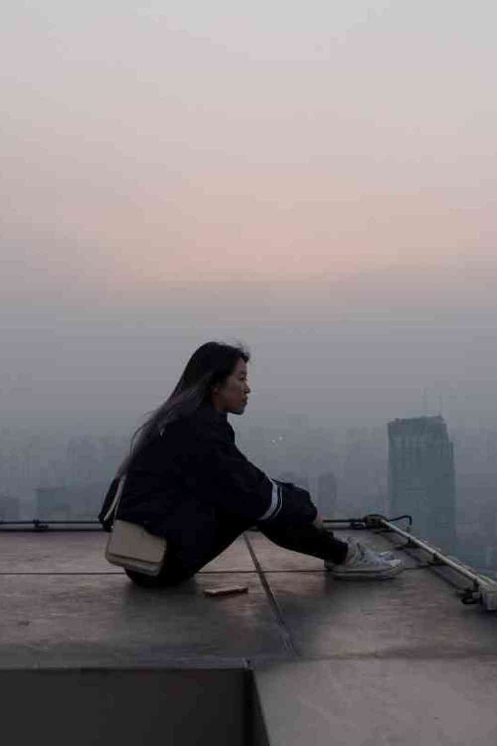 post-travel blues girl sitting on rooftop on a cloudy day looking pensive