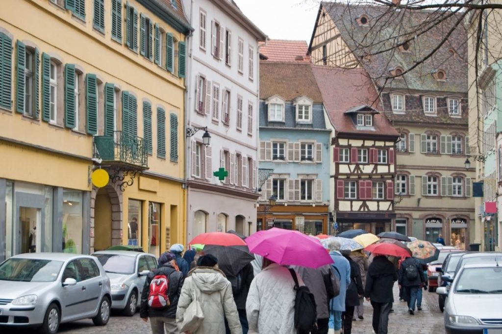 people taking a walking tour of a European city with coats and umbrellas
