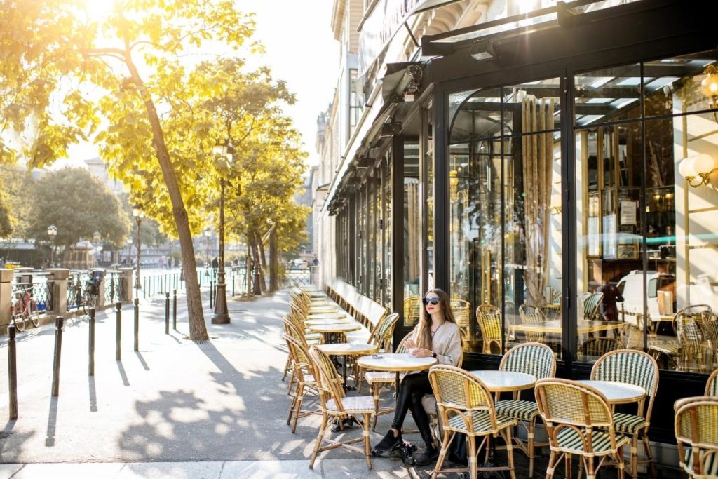 a girl with sunglasses sitting in a cafe in paris, france