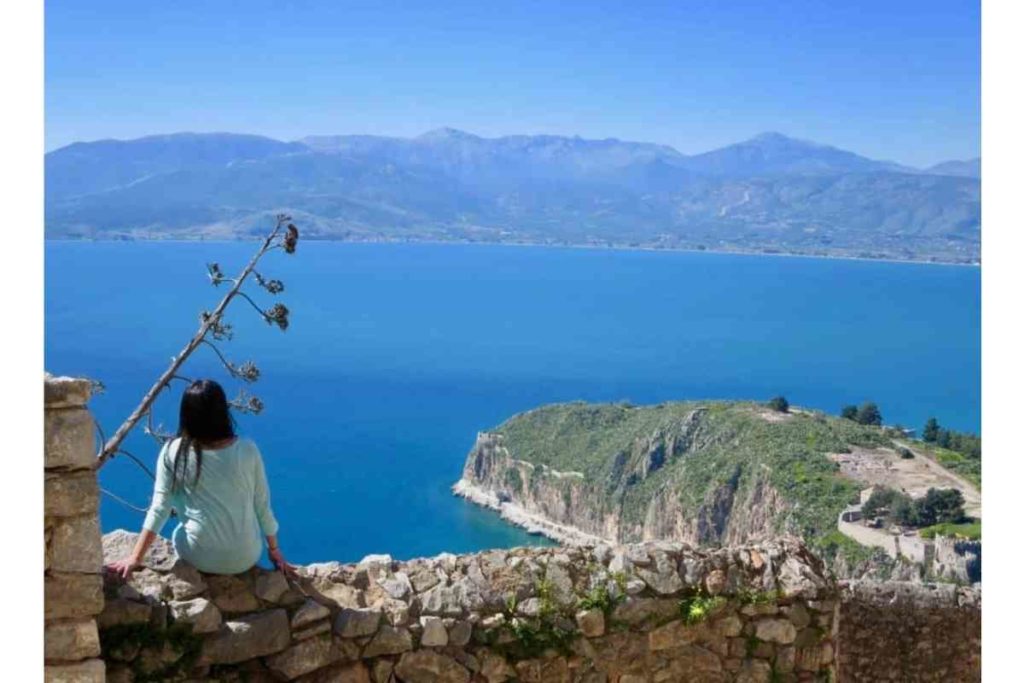 girl with black hair looking out to Aegean sea and mountains in Nafplio Greece