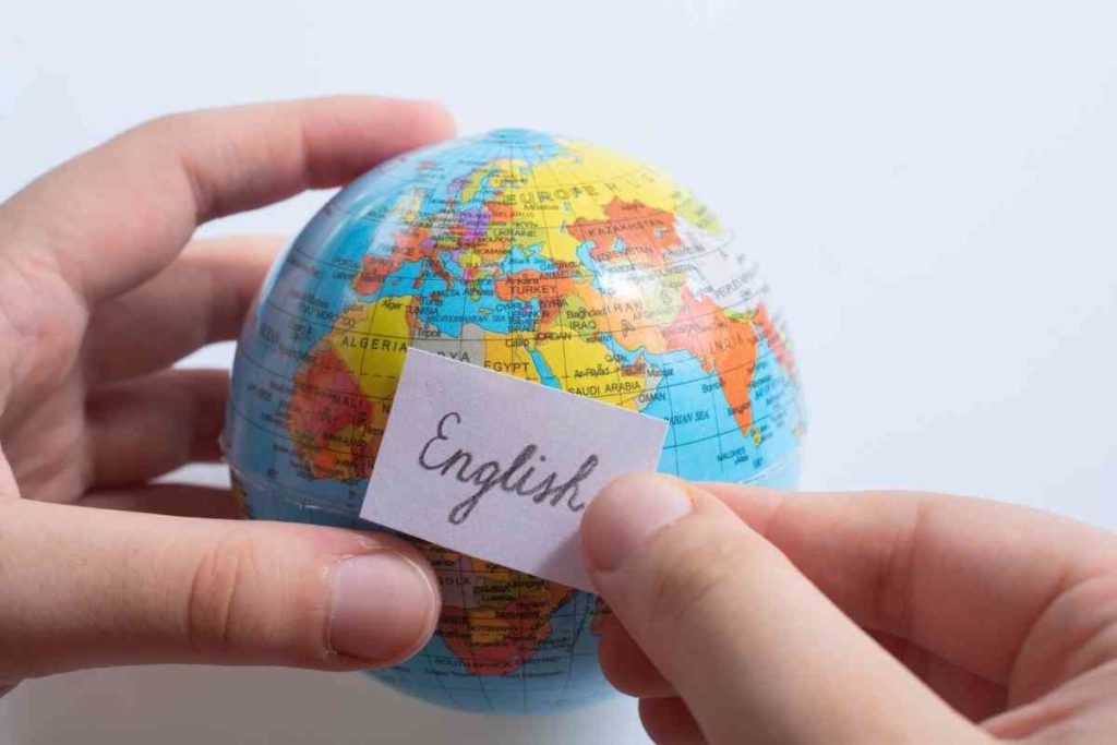a person holding a toy globe and holding the word "English" in front of it