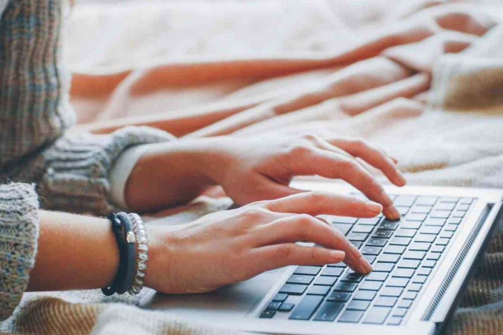 close up of a girl's hands as she's typing on her computer for her remote job