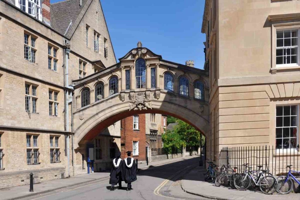 2 graduates walking through historic college campus on a sunny day