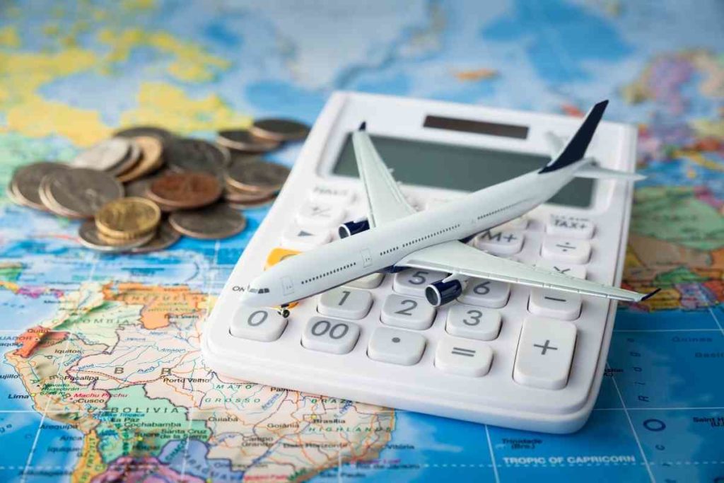 calculator with a toy airplane coins and a world map