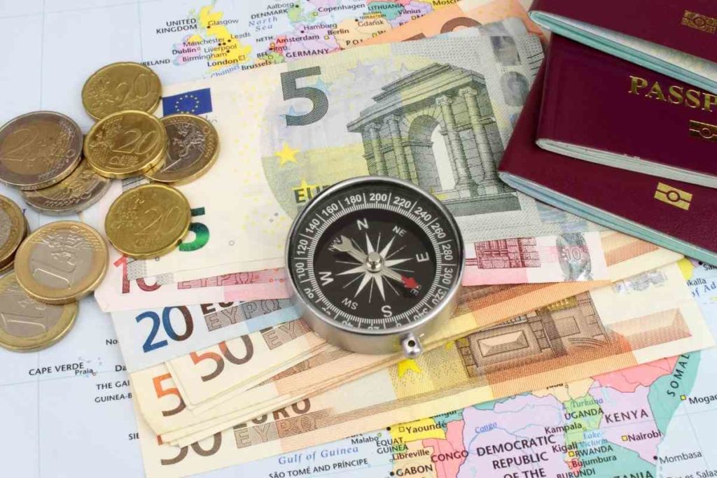 A close up of euros with coins European passports a compass and a map of Europe
