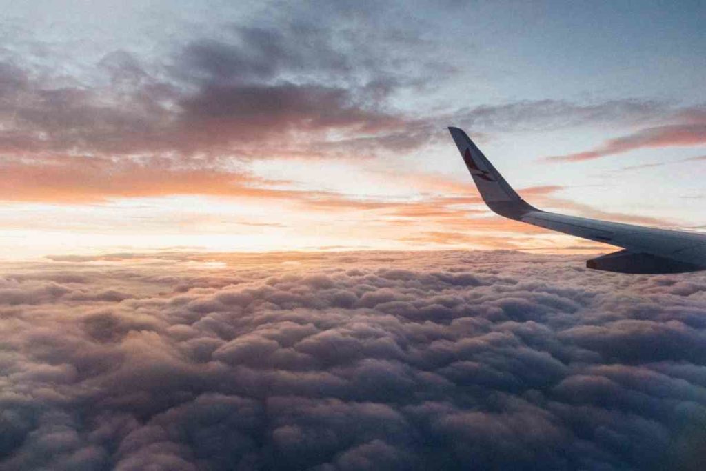 airplane wing flying above the clouds at sunset