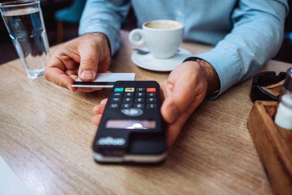 a man paying his coffee with his card with a card machine at a coffee shop