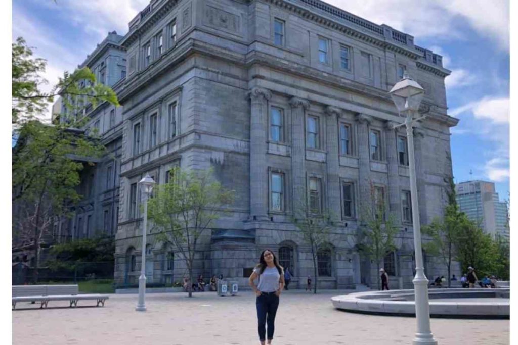 girl standing in front of building in montreal, canada with grey shirt and dark jeans
