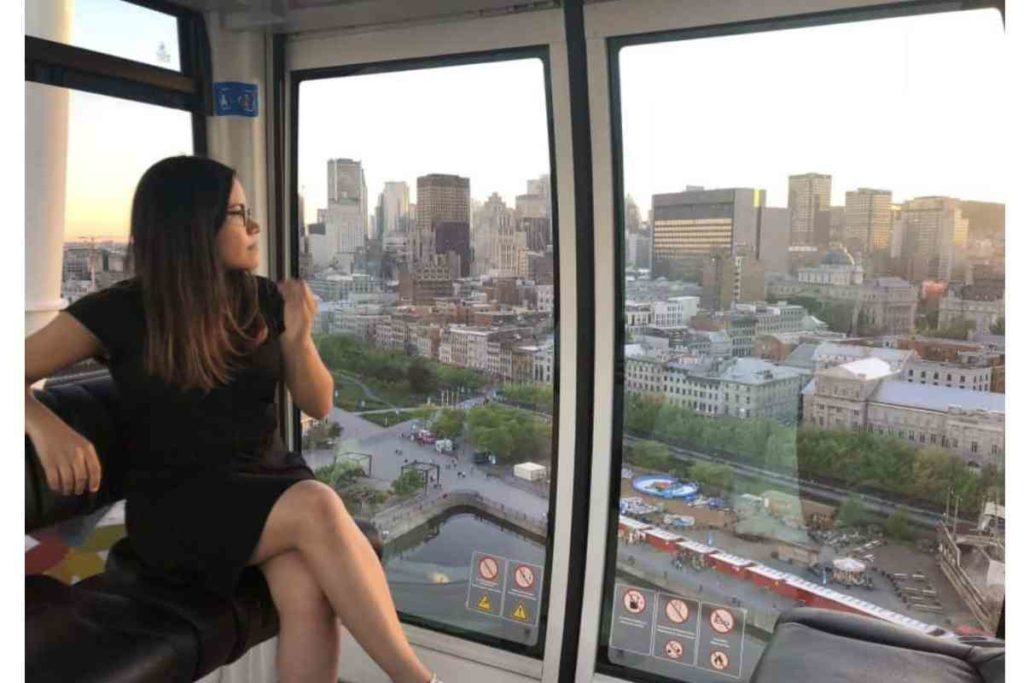 girl with black dress and glasses sitting inside ferris wheel in montreal, canada