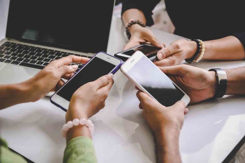 people standing together holding their phones together communicating