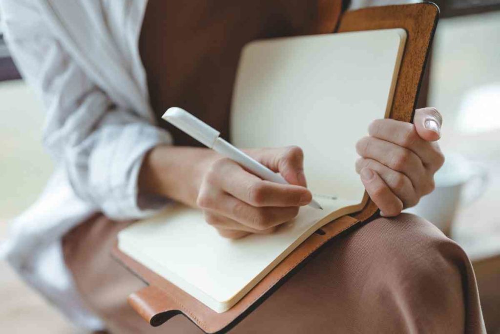 girl writing in her journal with a white pen