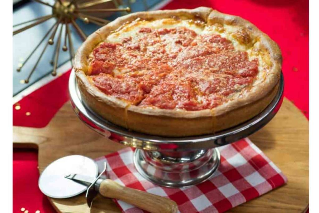 deep dish pizza with cutter and red and white checkered napkin