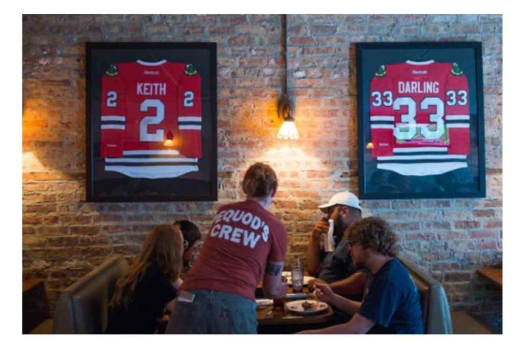 Chicago pizzeria with 2 photos hanging of Chicago Blackhawks jerseys and people eating pizza