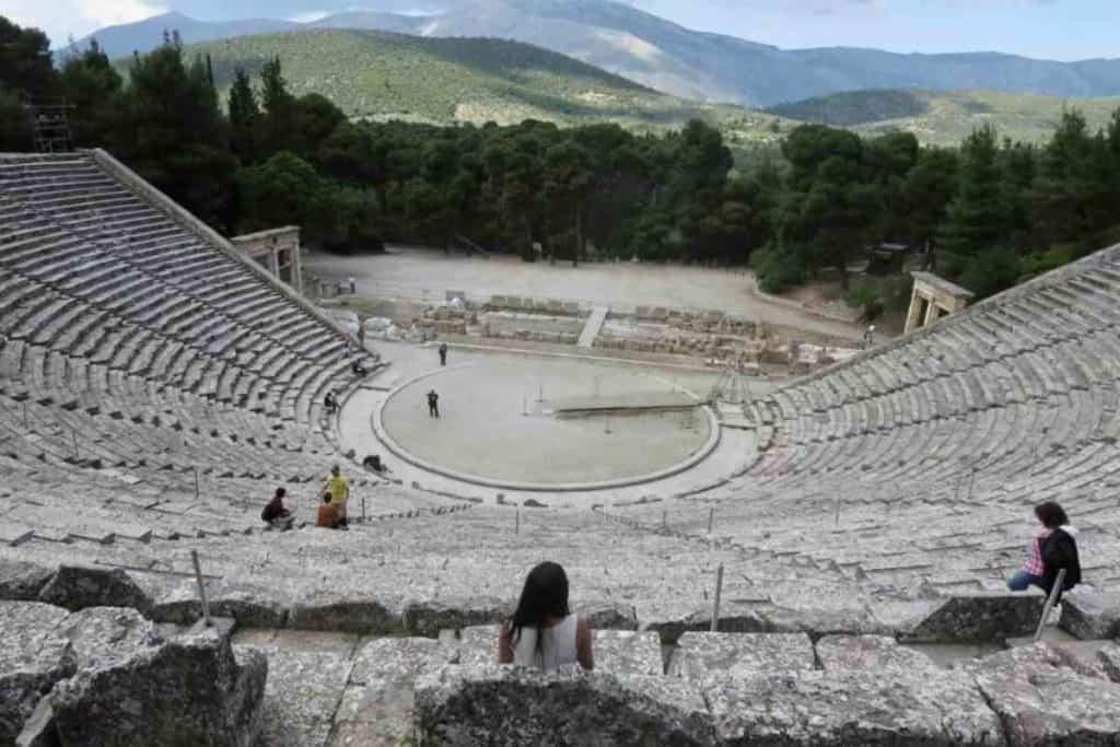 ni de aqui ni de alla girl sitting in Greek theater ruin overlooking mountains
