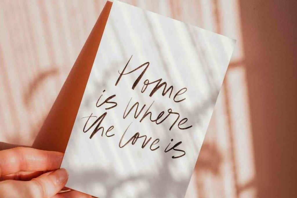 ni de aqui ni de alla girl holding post card that reads home is where the love is