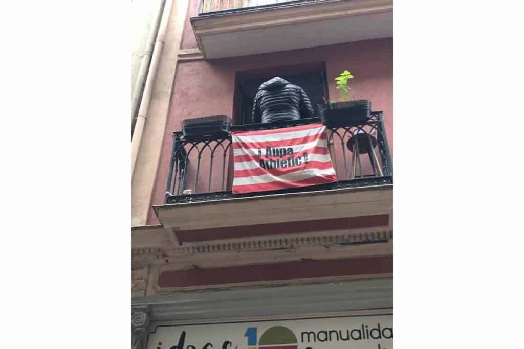 a balcony in the historic center of Bilbao with the flag of the Athletic Bilbao soccer team that says Aupa Athletic! 