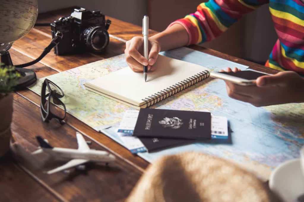 Best Safety Tips as a Solo Latina Traveler   girl planning a trip with her phone on a world map 
