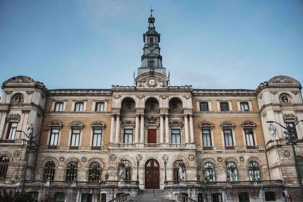 Marvel at the classical architecture of Bilbao's City Hall during a Bilbao tour, with its stately beige and white facade, adorned with statues and ornate stonework