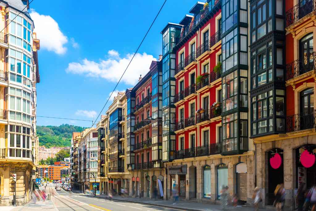 A vibrant Bilbao free walking tour down city streets, where the dance of colors on traditional buildings meets the modern blur of passersby and tramlines.