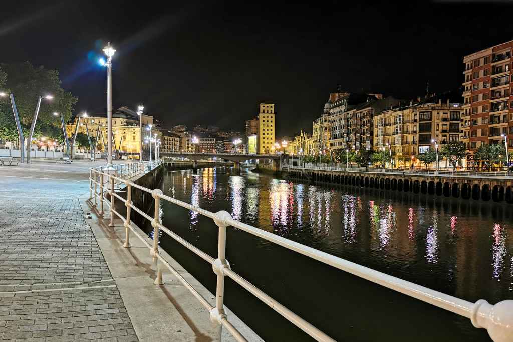 Discover Bilbao at night on a free ghost walking tour, where the riverfront comes alive with the golden glow of lamps, reflecting off the water and lighting up the diverse architecture.